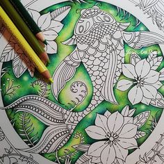 a coloring book page with a fish and flowers on it, surrounded by pencils