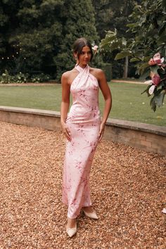 a woman wearing a pink dress standing in gravel