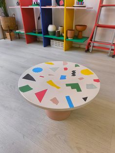 a white table sitting on top of a hard wood floor next to shelves filled with vases