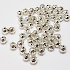 many silver balls are scattered together on a white surface, with spacers in the middle