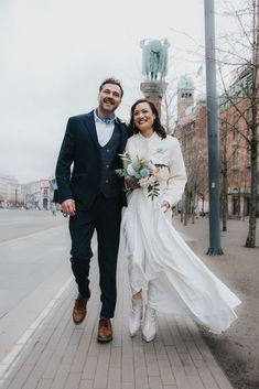 a bride and groom are walking down the street