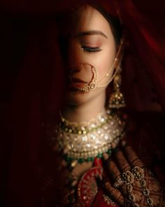 a woman with her eyes closed and nose ring in front of her face, wearing a bridal outfit