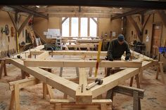 a man working in a wood shop with lots of work on the tables and benches