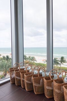 wicker baskets lined up on the floor in front of large windows with ocean view