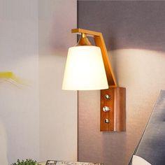 a lamp that is on the side of a wall next to a table with a book