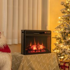 a white dog sitting in front of a fireplace with a christmas tree next to it