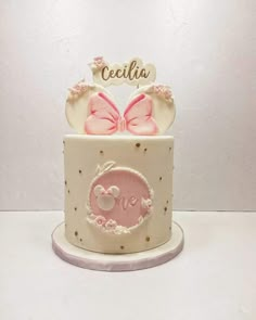 a pink and white cake with two bows on top that says cecija in spanish