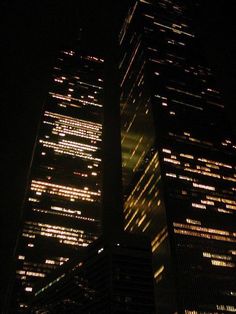 a very tall building with lots of lights on it's sides in the dark