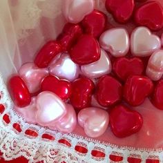 red and white heart shaped candy in a pink bag on a lace doily with crochet border