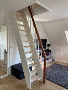 there is a white stair case in the living room with wood flooring and carpet