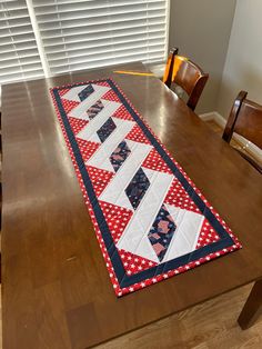 the table runner is made from red, white and blue quilts on top of a wooden table