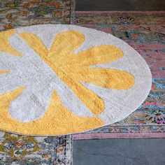 a yellow and white rug sitting on top of a carpet covered in lots of different colors