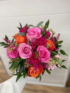 a bouquet of pink and orange flowers in someone's hand