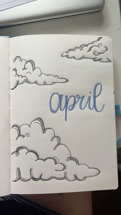 an open notebook with the word april written in blue ink on it and clouds above