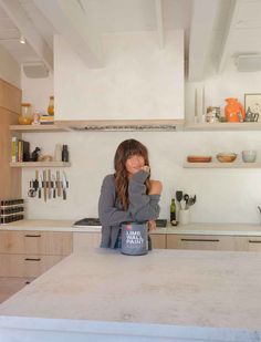 a woman sitting at a kitchen counter with her hand on her face and looking off to the side