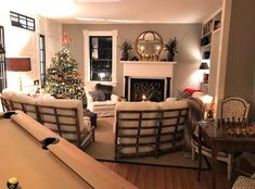 a living room filled with furniture and a christmas tree in front of a fire place