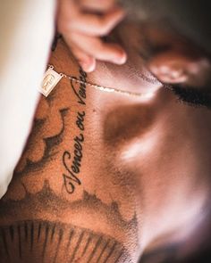 a close up of a person with tattoos on his chest and hand behind the neck