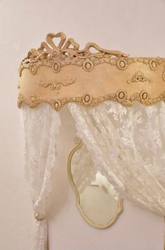 an ornate gold mirror hanging on the wall next to a white drapes and curtain