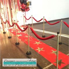 a red carpet with gold stars on it and some poles in front of the entrance