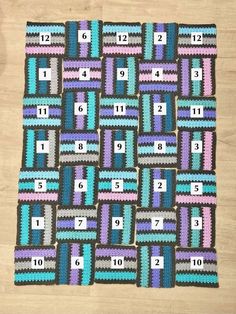 a crocheted blanket with numbers and squares on the front, sitting on top of a wooden floor