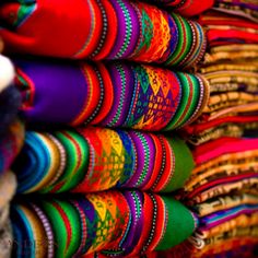 many colorful fabrics are stacked on top of each other