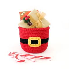 a crocheted christmas basket with candy canes and candies on the side