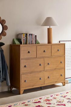 a wooden dresser sitting next to a lamp on top of a rug