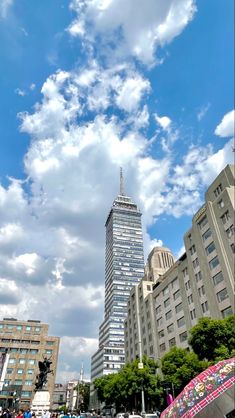 people are walking on the sidewalk in front of tall buildings under a cloudy blue sky