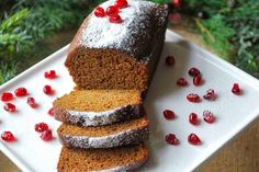 slices of cake on a white plate with pomegranates around the edges