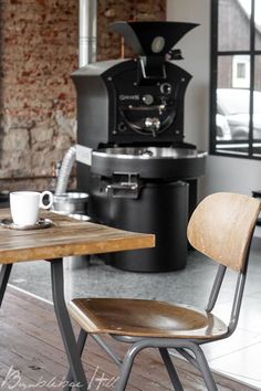 two wooden chairs sitting next to each other in front of a table with a cup on it