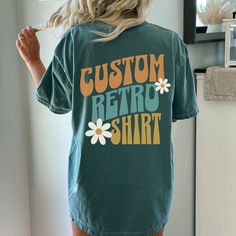 Show off your retro style with this Custom 3 Word Retro Font Oversized T-shirt. The vintage font is sure to make a statement and bring you back to the fun, classic days of the past. And the added flowers give you a groovy vibe. With roomy, oversized fit, you'll be able to express yourself with comfort and ease. Ideal for any casual occasion, this T-shirt's retro look will take your wardrobe to the next level. This custom design T-shirt comes in your choice of 12 vibrant colors, perfect for makin Retro Crew Neck T-shirt With Lettering, Vintage Short Sleeve T-shirt With Lettering, Retro Graphic Print Crew Neck Top, Retro Crew Neck Top With Graphic Print, Retro Cotton Shirt With Letter Print, Oversized Vintage Shirt With Letter Print, Vintage Text Print Crew Neck Shirt, Vintage Summer Tops With Custom Print, Vintage Custom Print Tops For Summer