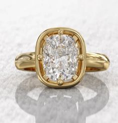 a yellow gold ring with a cushion cut diamond in the center on a white background