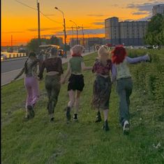 several people walking on the side of a road at sunset