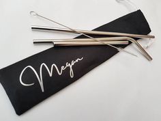 three stainless steel straws with the word merry written on them in white ink next to each other