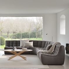 a living room filled with furniture next to a large window covered in lots of windows