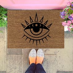 a person standing in front of a door mat with an eye on it