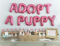 pink balloon letters that say adopt a puppy on top of a dresser with stuffed animals