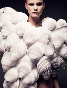 a woman is standing in front of a large pile of white paper balls on her head