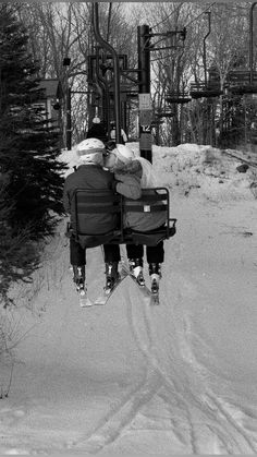 two people are sitting on a chairlift in the snow with their backs to each other