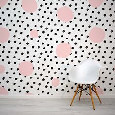 a white chair sitting in front of a wall with black and pink polka dots on it