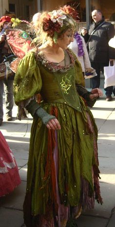 a woman dressed in green is walking down the street