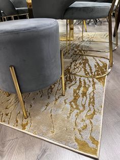 two grey chairs sitting on top of a rug in a room with gold trimmings