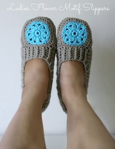 someone is wearing crocheted slippers with blue flowers on them