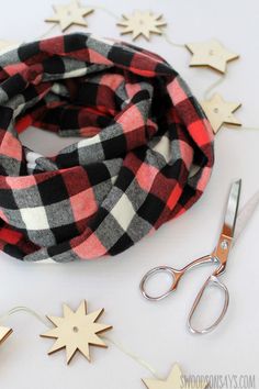 a scarf, scissors and some cut out stars on a white table with red and black flannel