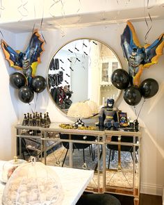 balloons and decorations are on the table in front of a mirror with bats hanging from it