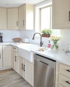 a clean kitchen with white cabinets and stainless steel dishwasher in the center island