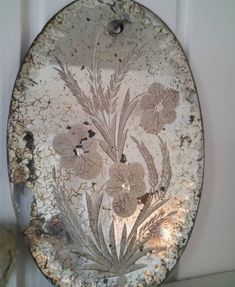 an old plate with flowers on it is hanging on the wall next to a teddy bear