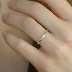 a woman's hand with a wedding ring on her left hand, wearing a diamond band