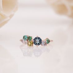 three different colored stones on top of each other in an engagement ring with rose petals