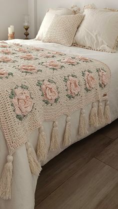 a white bed with pink roses and tassels on it